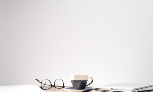 A beautiful shot of optical glasses and a cup on a table with a clean white background - space for text, perfect for article and magazine backgrounds