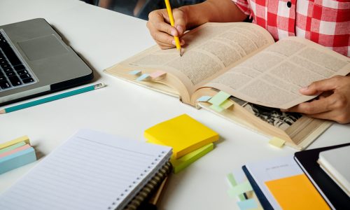 Education concept. Students studying and brainstorming campus concept. Close up of students discussing their subject on books textbooks and writing to notebook. Seclective focus.