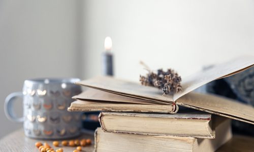 Cozy home composition with a stack of books on a blurred background, copy space.