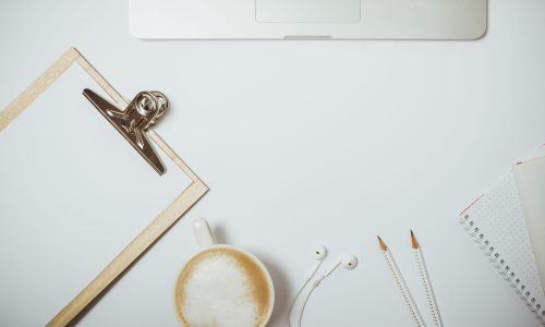 Creative desktop with laptop, coffee and stationery on white table. Top view, Flat lay