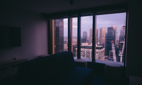 A small apartment with a large window with a view of an urban city architecture