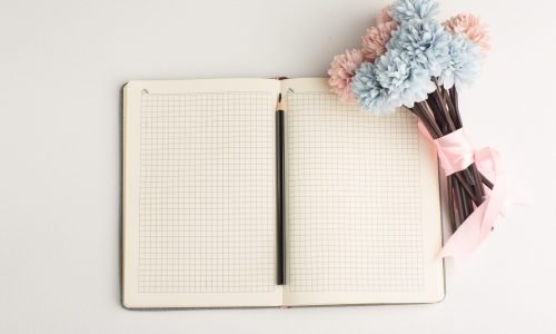 top-view-open-notepad-with-flower-pencil-white-surface
