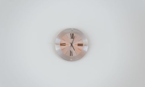 A wide shot of a rose gold wall clock on a white wall